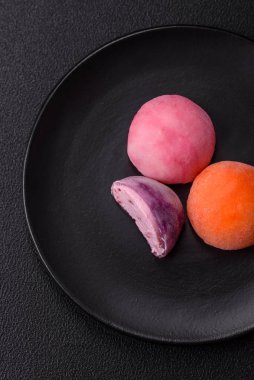 Lezzetli Asya mochi tatlısı pirinç hamuru kabuğu ve koyu beton arka planda meyveler.