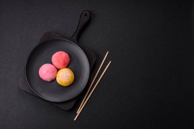 Lezzetli Asya mochi tatlısı pirinç hamuru kabuğu ve koyu beton arka planda meyveler.