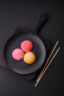 Lezzetli Asya mochi tatlısı pirinç hamuru kabuğu ve koyu beton arka planda meyveler.