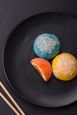 Lezzetli Asya mochi tatlısı pirinç hamuru kabuğu ve koyu beton arka planda meyveler.