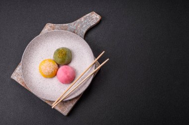Lezzetli Asya mochi tatlısı pirinç hamuru kabuğu ve koyu beton arka planda meyveler.