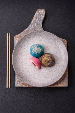 Lezzetli Asya mochi tatlısı pirinç hamuru kabuğu ve koyu beton arka planda meyveler.