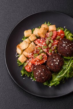 Lezzetli kızarmış falafel nohuttan, kimyondan, tuzlu humus ve baharatlı koyu beton arka planda.