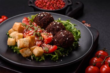 Lezzetli kızarmış falafel nohuttan, kimyondan, tuzlu humus ve baharatlı koyu beton arka planda.