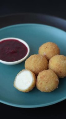 Ekmekli peynirli patates kızartması topları ya da koyu beton arka planda tatlı çilek soslu camembert peyniri.