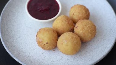 Ekmekli peynirli patates kızartması topları ya da koyu beton arka planda tatlı çilek soslu camembert peyniri.