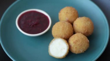 Ekmekli peynirli patates kızartması topları ya da koyu beton arka planda tatlı çilek soslu camembert peyniri.