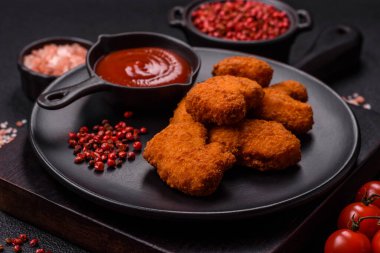 Delicious fresh crispy chicken nuggets on a dark concrete background. Unhealthy food, fast food