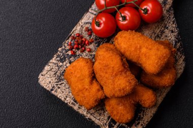 Delicious fresh crispy chicken nuggets on a dark concrete background. Unhealthy food, fast food