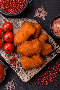 Delicious fresh crispy chicken nuggets on a dark concrete background. Unhealthy food, fast food