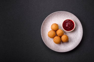 Ekmekli peynirli patates kızartması topları ya da koyu beton arka planda tatlı çilek soslu camembert peyniri.