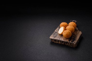 Ekmekli peynirli patates kızartması topları ya da koyu beton arka planda tatlı çilek soslu camembert peyniri.