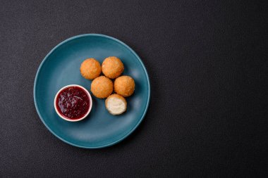 Ekmekli peynirli patates kızartması topları ya da koyu beton arka planda tatlı çilek soslu camembert peyniri.