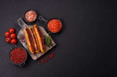 Koyu beton arka planda tuz, baharat ve otlu tavuk veya domuz sosisi.