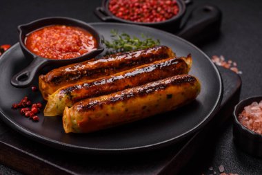 Koyu beton arka planda tuz, baharat ve otlu tavuk veya domuz sosisi.