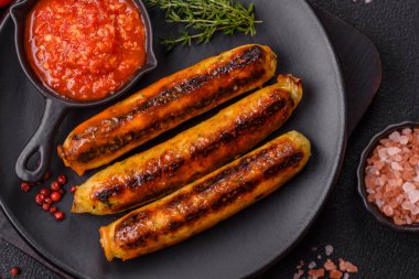 Koyu beton arka planda tuz, baharat ve otlu tavuk veya domuz sosisi.