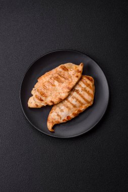 Lezzetli taze ızgara tavuk filetosu, esrarlı baharatlar ve çimento kaplı otlar. Ateşte pişirilmiş bir tabak.