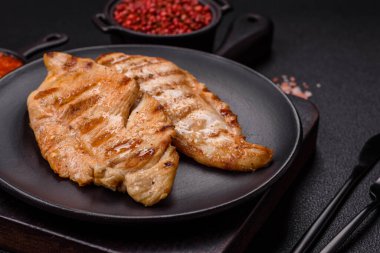 Lezzetli taze ızgara tavuk filetosu, esrarlı baharatlar ve çimento kaplı otlar. Ateşte pişirilmiş bir tabak.