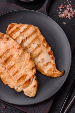 Lezzetli taze ızgara tavuk filetosu, esrarlı baharatlar ve çimento kaplı otlar. Ateşte pişirilmiş bir tabak.