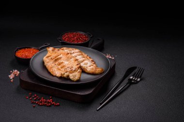 Lezzetli taze ızgara tavuk filetosu, esrarlı baharatlar ve çimento kaplı otlar. Ateşte pişirilmiş bir tabak.