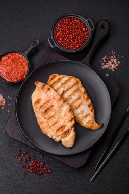 Lezzetli taze ızgara tavuk filetosu, esrarlı baharatlar ve çimento kaplı otlar. Ateşte pişirilmiş bir tabak.