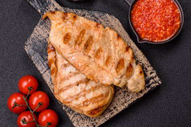 Lezzetli taze ızgara tavuk filetosu, esrarlı baharatlar ve çimento kaplı otlar. Ateşte pişirilmiş bir tabak.