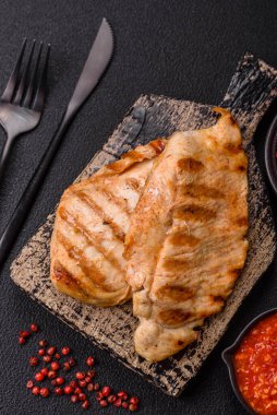 Lezzetli taze ızgara tavuk filetosu, esrarlı baharatlar ve çimento kaplı otlar. Ateşte pişirilmiş bir tabak.