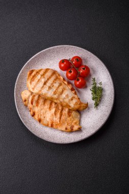 Lezzetli taze ızgara tavuk filetosu, esrarlı baharatlar ve çimento kaplı otlar. Ateşte pişirilmiş bir tabak.