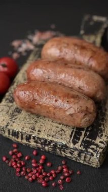 Koyu beton arka planda ızgarada pişirilmiş tuzlu, baharatlı ve otlu tavuk veya domuz sosisi.