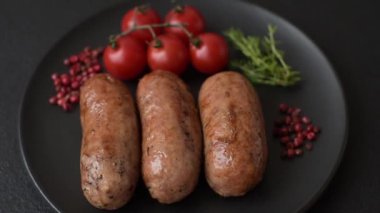Koyu beton arka planda ızgarada pişirilmiş tuzlu, baharatlı ve otlu tavuk veya domuz sosisi.