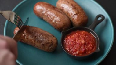 Koyu beton arka planda ızgarada pişirilmiş tuzlu, baharatlı ve otlu tavuk veya domuz sosisi.