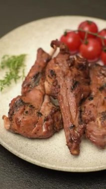 Izgarada pişmiş biftek, tuz, baharat ve otlarla birlikte koyu beton bir arka planda.