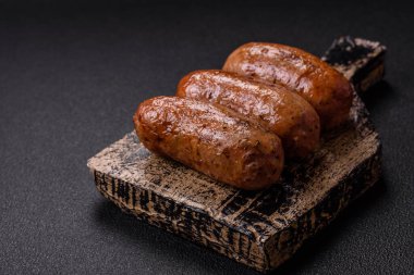 Koyu beton arka planda ızgarada pişirilmiş tuzlu, baharatlı ve otlu tavuk veya domuz sosisi.