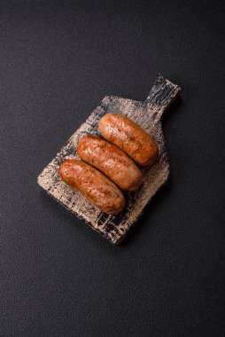 Koyu beton arka planda ızgarada pişirilmiş tuzlu, baharatlı ve otlu tavuk veya domuz sosisi.