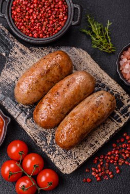 Koyu beton arka planda ızgarada pişirilmiş tuzlu, baharatlı ve otlu tavuk veya domuz sosisi.