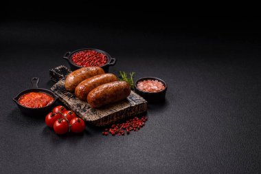 Koyu beton arka planda ızgarada pişirilmiş tuzlu, baharatlı ve otlu tavuk veya domuz sosisi.