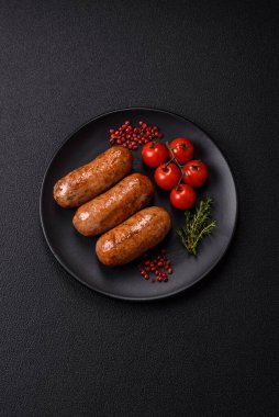 Koyu beton arka planda ızgarada pişirilmiş tuzlu, baharatlı ve otlu tavuk veya domuz sosisi.