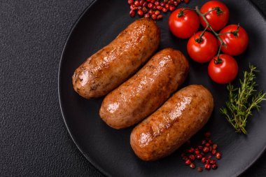 Koyu beton arka planda ızgarada pişirilmiş tuzlu, baharatlı ve otlu tavuk veya domuz sosisi.