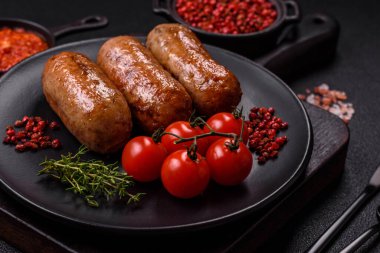 Koyu beton arka planda ızgarada pişirilmiş tuzlu, baharatlı ve otlu tavuk veya domuz sosisi.