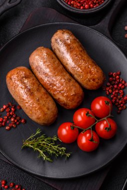 Koyu beton arka planda ızgarada pişirilmiş tuzlu, baharatlı ve otlu tavuk veya domuz sosisi.