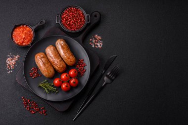 Koyu beton arka planda ızgarada pişirilmiş tuzlu, baharatlı ve otlu tavuk veya domuz sosisi.