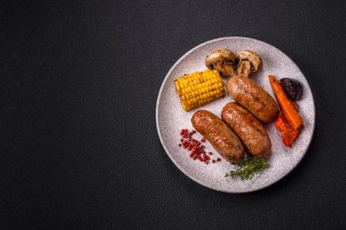 Koyu beton arka planda ızgarada pişirilmiş tuzlu, baharatlı ve otlu tavuk veya domuz sosisi.