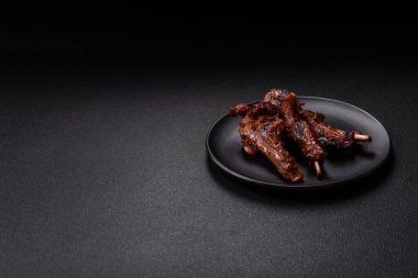 Izgarada pişmiş biftek, tuz, baharat ve otlarla birlikte koyu beton bir arka planda.