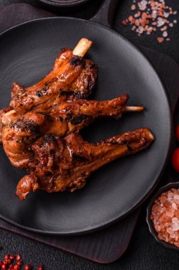 Izgarada pişmiş biftek, tuz, baharat ve otlarla birlikte koyu beton bir arka planda.