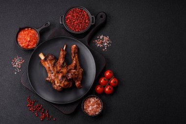 Izgarada pişmiş biftek, tuz, baharat ve otlarla birlikte koyu beton bir arka planda.