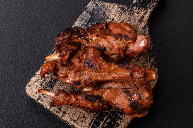 Izgarada pişmiş biftek, tuz, baharat ve otlarla birlikte koyu beton bir arka planda.