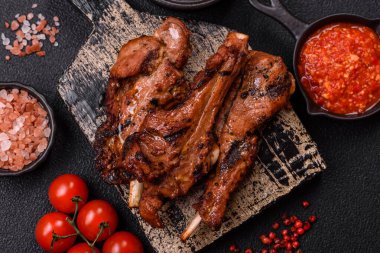 Izgarada pişmiş biftek, tuz, baharat ve otlarla birlikte koyu beton bir arka planda.