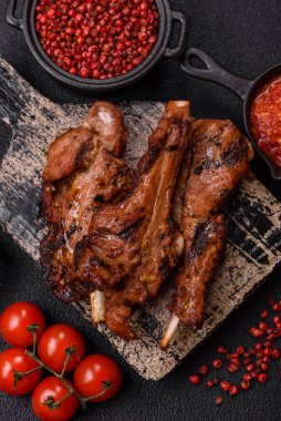 Izgarada pişmiş biftek, tuz, baharat ve otlarla birlikte koyu beton bir arka planda.