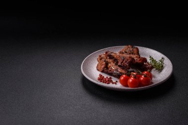 Izgarada pişmiş biftek, tuz, baharat ve otlarla birlikte koyu beton bir arka planda.