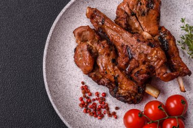 Izgarada pişmiş biftek, tuz, baharat ve otlarla birlikte koyu beton bir arka planda.